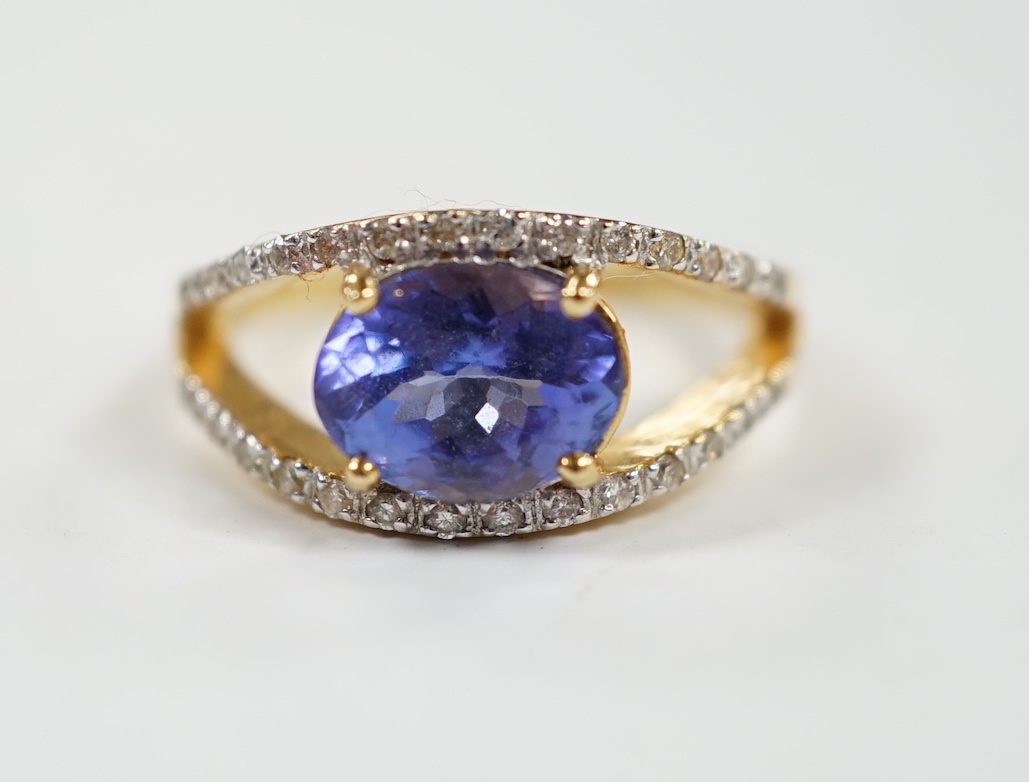 A modern 18ct gold and singe stone oval cut tanzanite ring, with diamond chip set borders, size N, gross weight 5 grams.